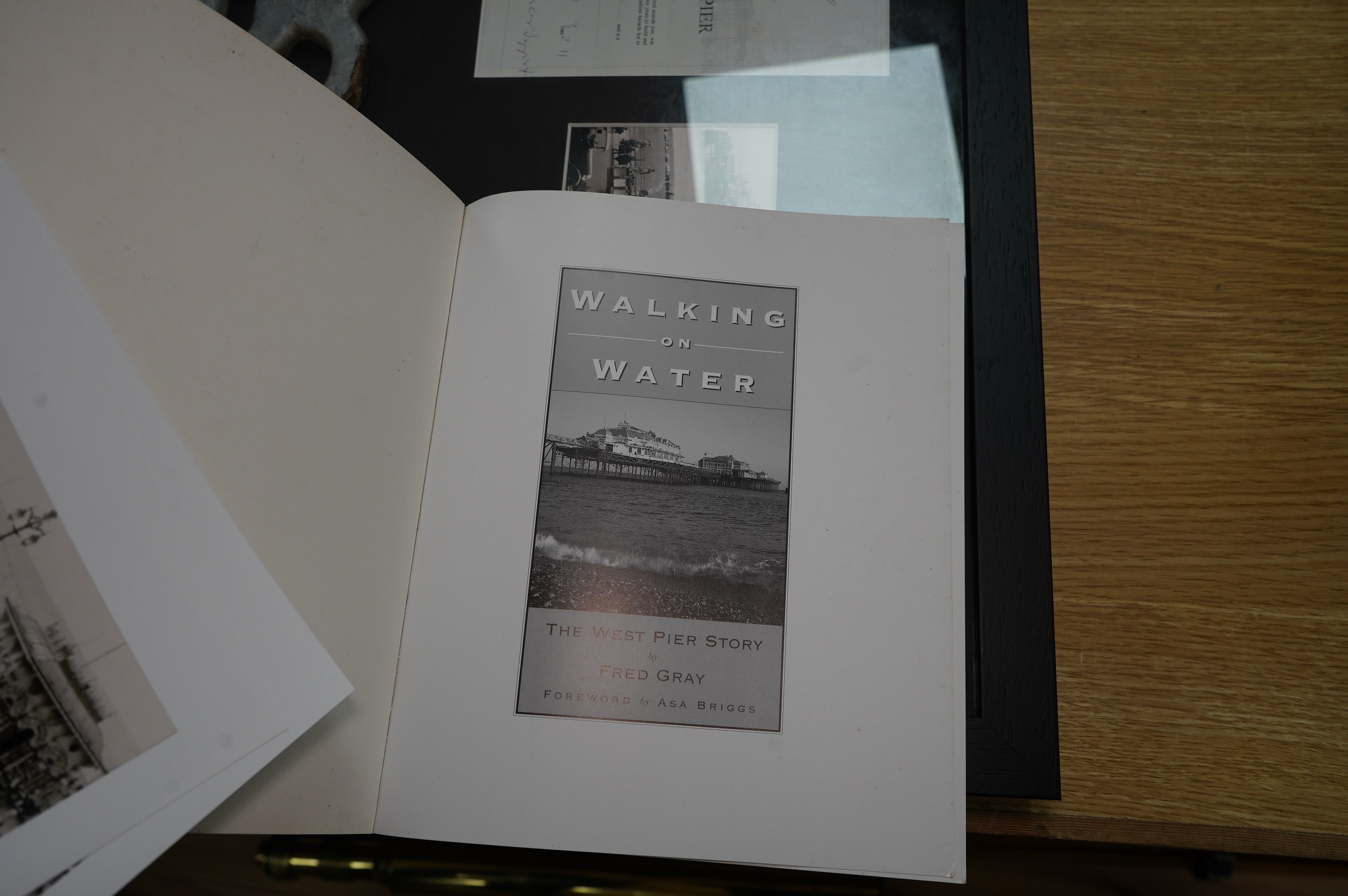 A framed part of the original frieze from the West Pier in Brighton, a photo and certificate, plus a book about the West Pier, 50cm wide, 40cm high. Condition - good